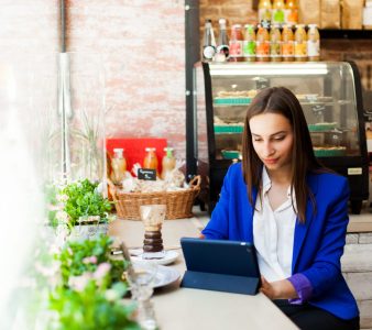 Woman works with a tablet at the table in a cafe