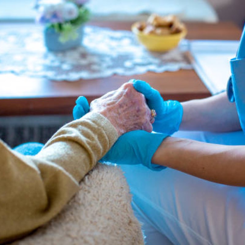 Young female doctor is holding her patient's hand, comforting her. Old lady is worried and doctor is there to take care of her every need. Old lady is in trusting hands.