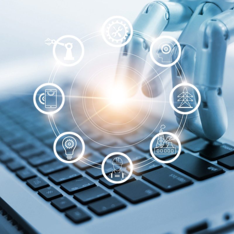 Hand of robotics connecting to industrial network connection on laptop. Artificial intelligence. Futuristic technology and manufacturing concept.